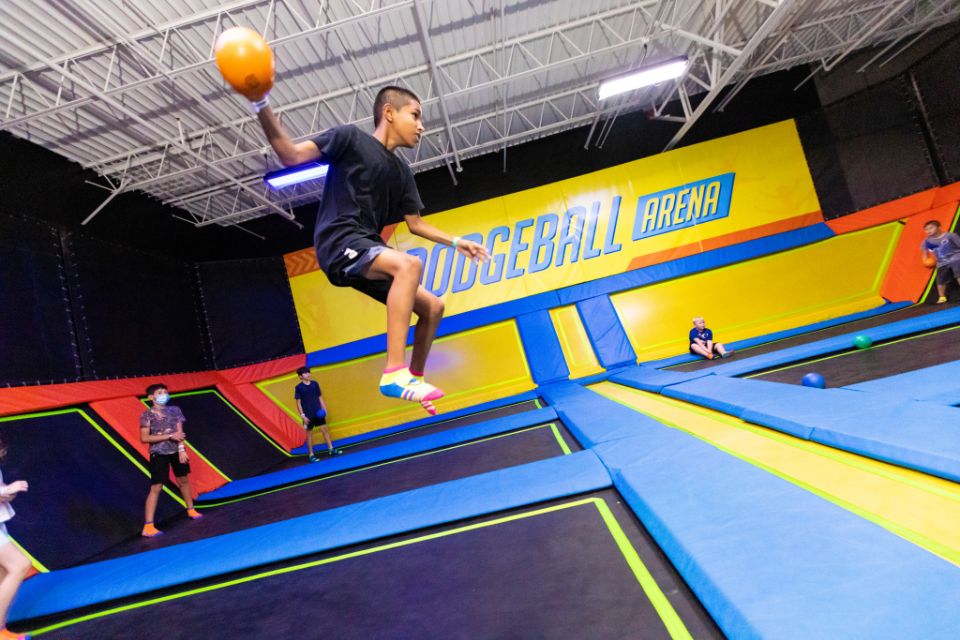 boy jumps on trampoline with ball during a dodgeball game