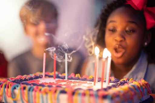 girl blowing out candles on a cake