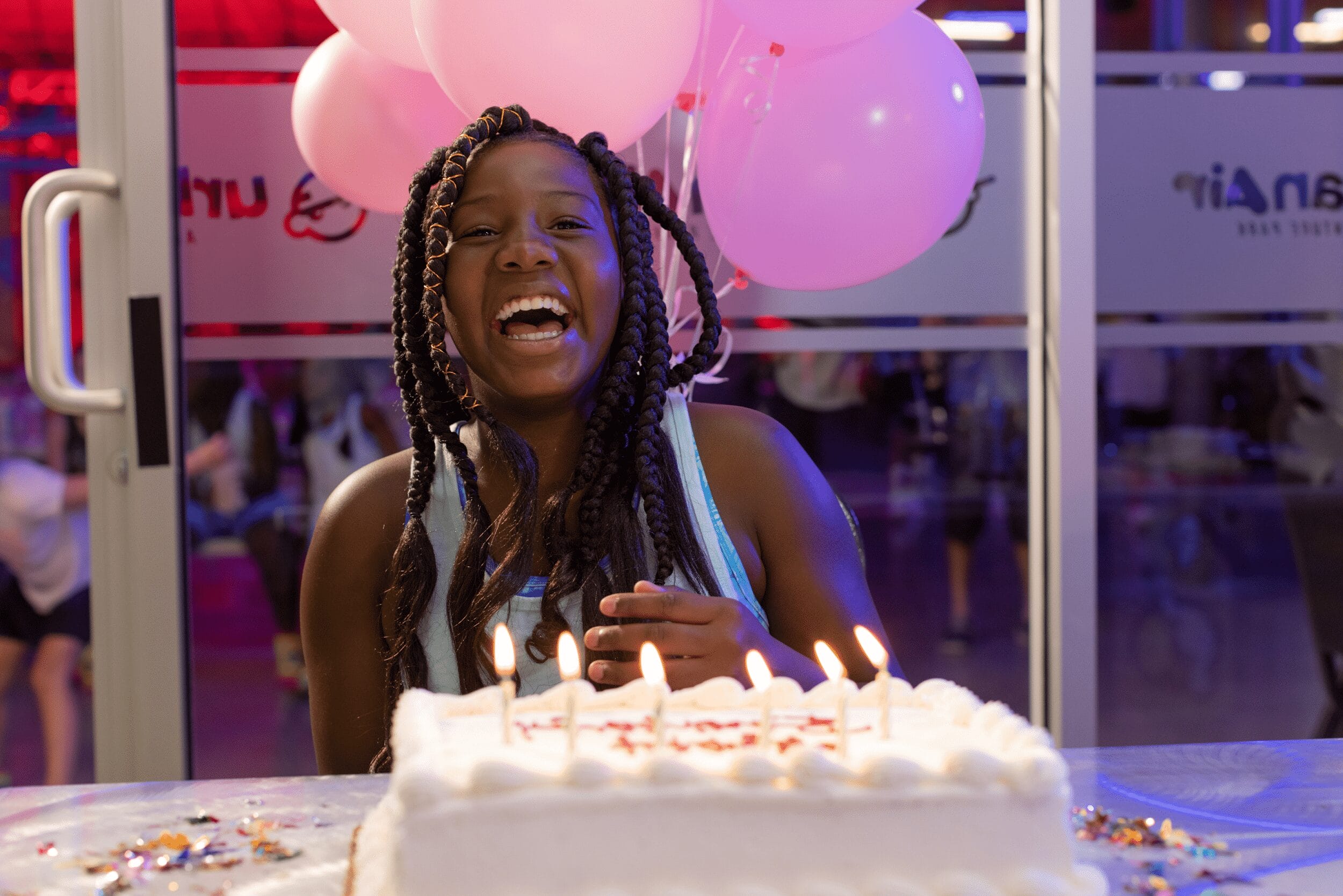 A young girl with a cake and balloons at Urban air 