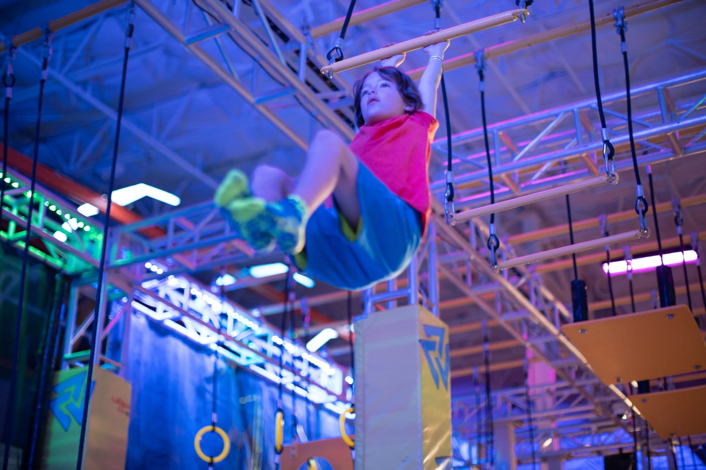boy swinging on an urban air warrior course
