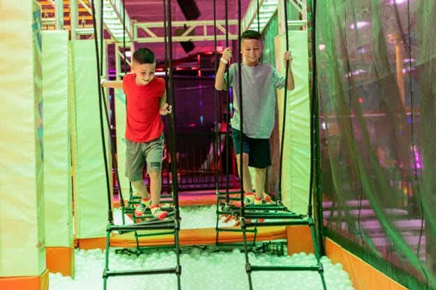 two boys having fun on an obstacle course at urban air