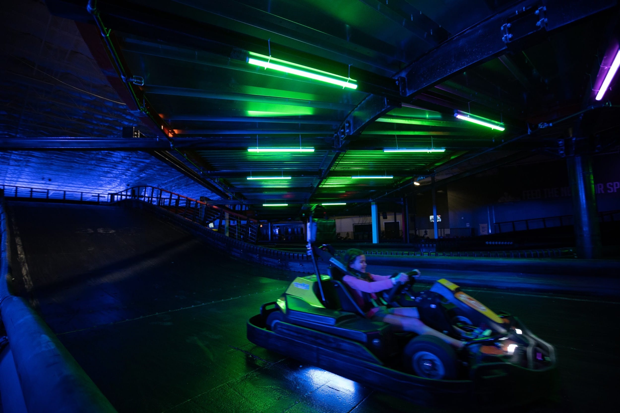 child driving a go kart on an indoor track